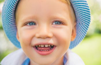 Smiling toddler wearing a blue hat.